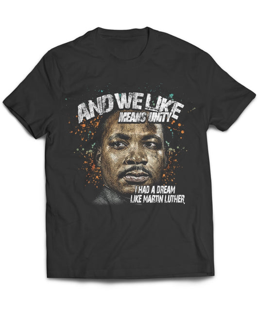 A black T-shirt featuring a colorful, stylized portrait of Martin Luther King Jr. The text above reads "AND WE LIKE MEANS UNITY!" and below the portrait, it says "I HAD A DREAM LIKE MARTIN LUTHER.